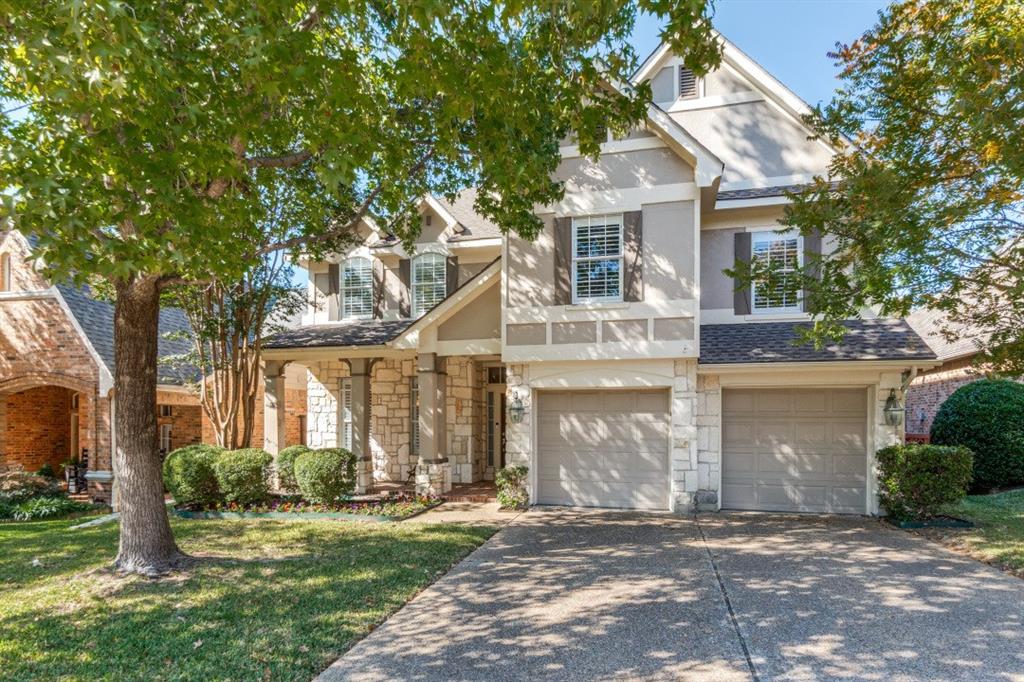 Traditional home with stucco siding, stone siding, a front yard, and a shingled roof