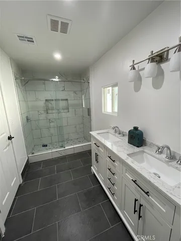 a bathroom with a double vanity sink a large mirror and a shower