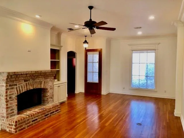 a view of an empty room with wooden floor a fireplace and a window