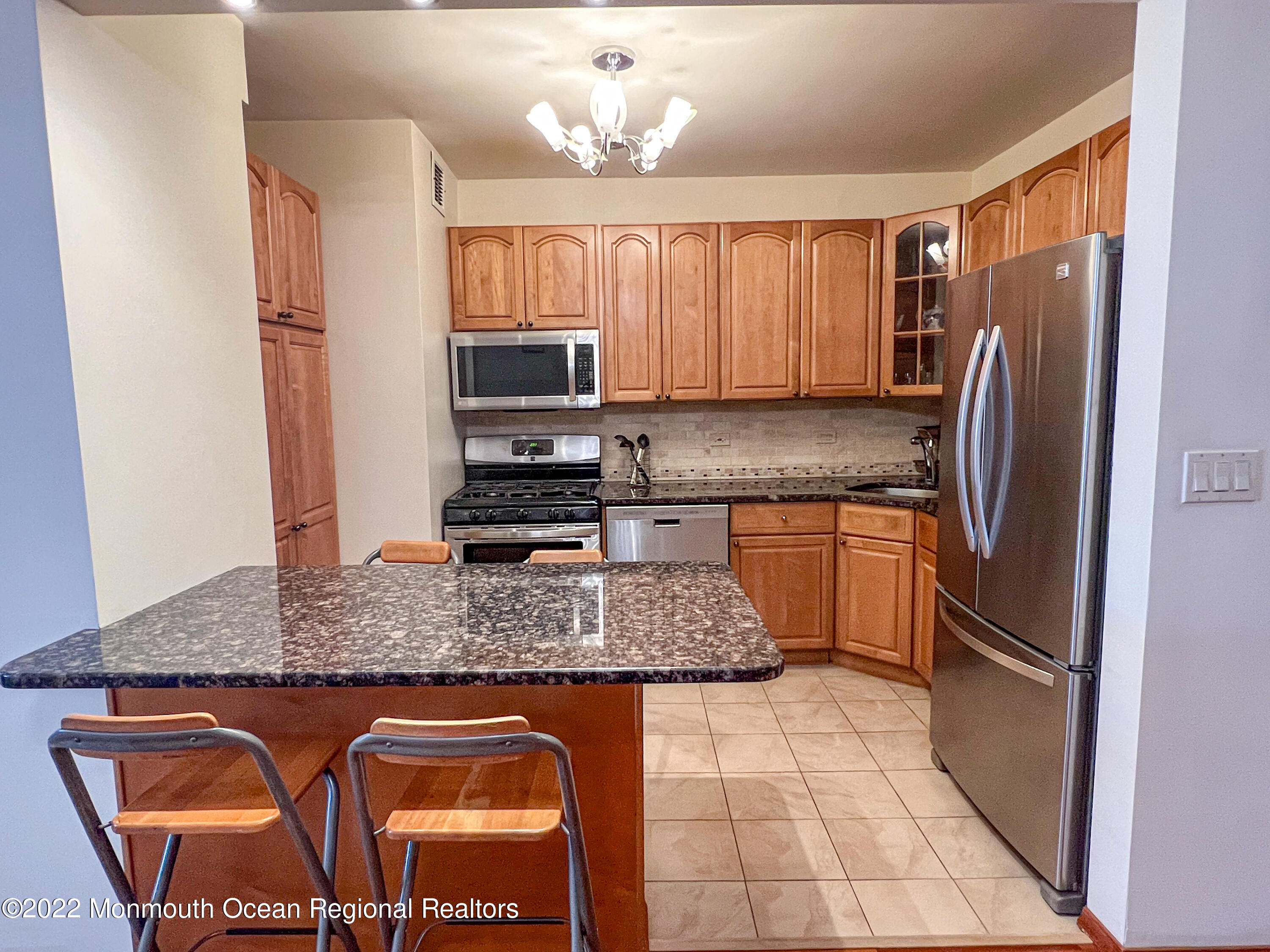 a kitchen with stainless steel appliances granite countertop a sink stove refrigerator and microwave