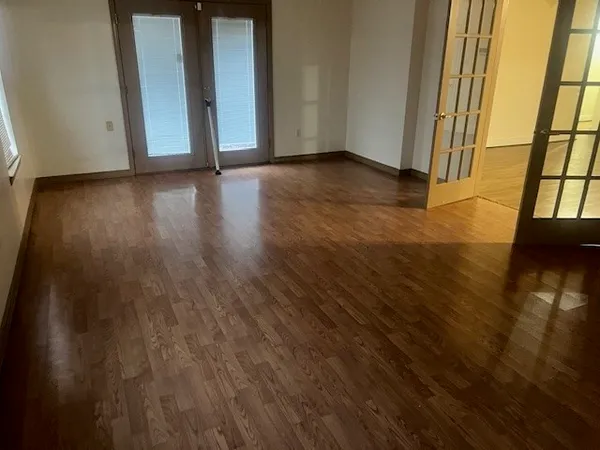 a view of an empty room with wooden floor and a window