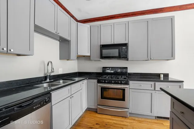 a kitchen with granite countertop a sink dishwasher stove and cabinets with wooden floor