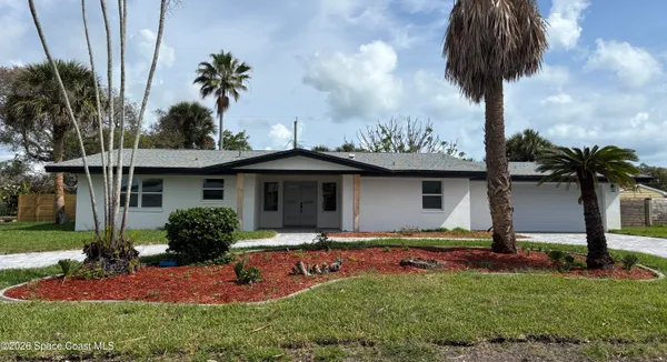 a front view of a house with garden and trees