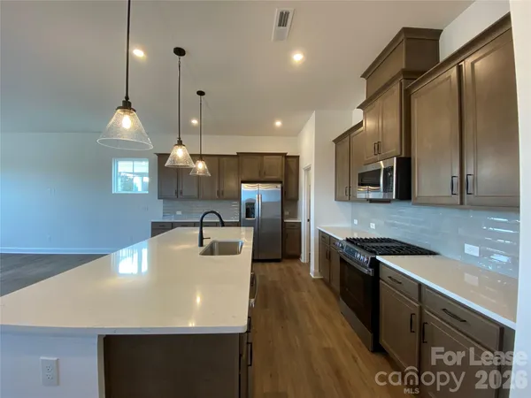 a kitchen with stainless steel appliances granite countertop a sink a stove top oven a counter space and cabinets