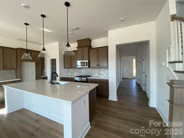 a kitchen with stainless steel appliances granite countertop a sink a refrigerator a stove and a wooden floors