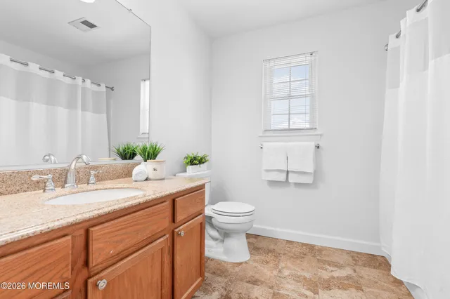a bathroom with a granite countertop sink mirror and a toilet