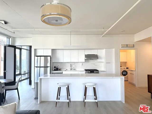 a kitchen with stainless steel appliances granite countertop a stove a refrigerator a microwave a dining table and chairs with wooden floor