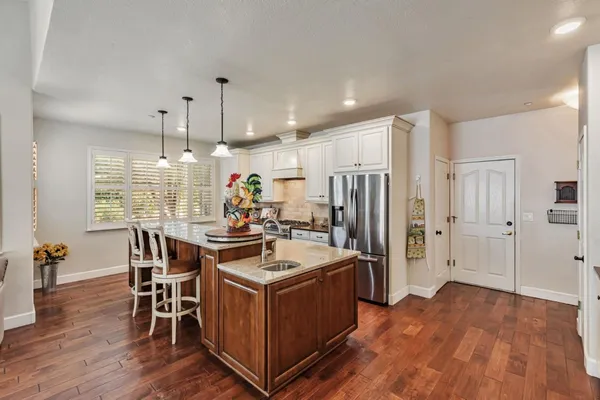 a kitchen with granite countertop a stove a sink a center island and cabinets