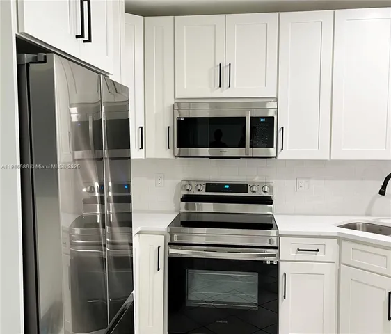 a kitchen with stainless steel appliances a refrigerator stove and white cabinets