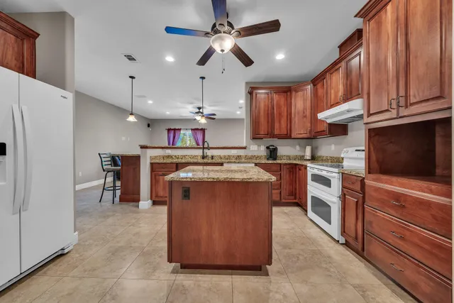 an empty room with wooden floor chandelier fan and windows