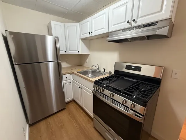 a kitchen with stainless steel appliances a refrigerator a stove and white cabinets