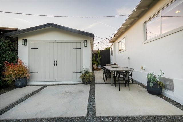 a view of a patio with a dining table and chairs and potted plants