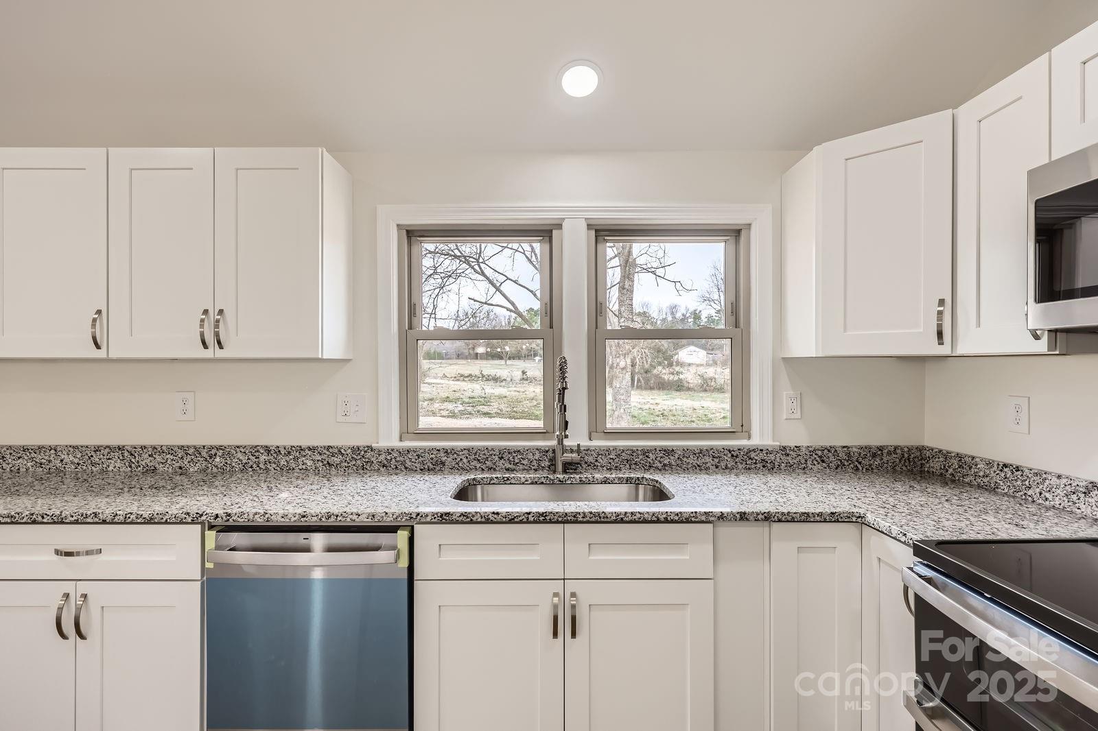 3225 Liberty Road Gold Hill, NC 28071 - Photo 8 of 24 a kitchen with stainless steel appliances granite countertop white cabinets and a window