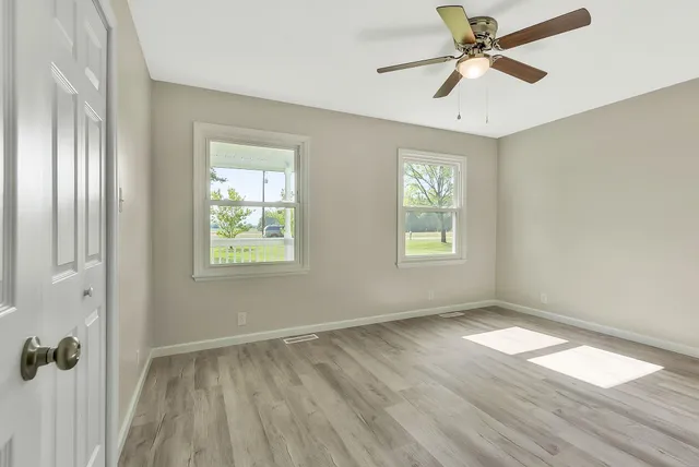 a view of empty room with wooden floor and fan