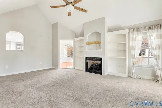 an empty room with windows fireplace and a kitchen view