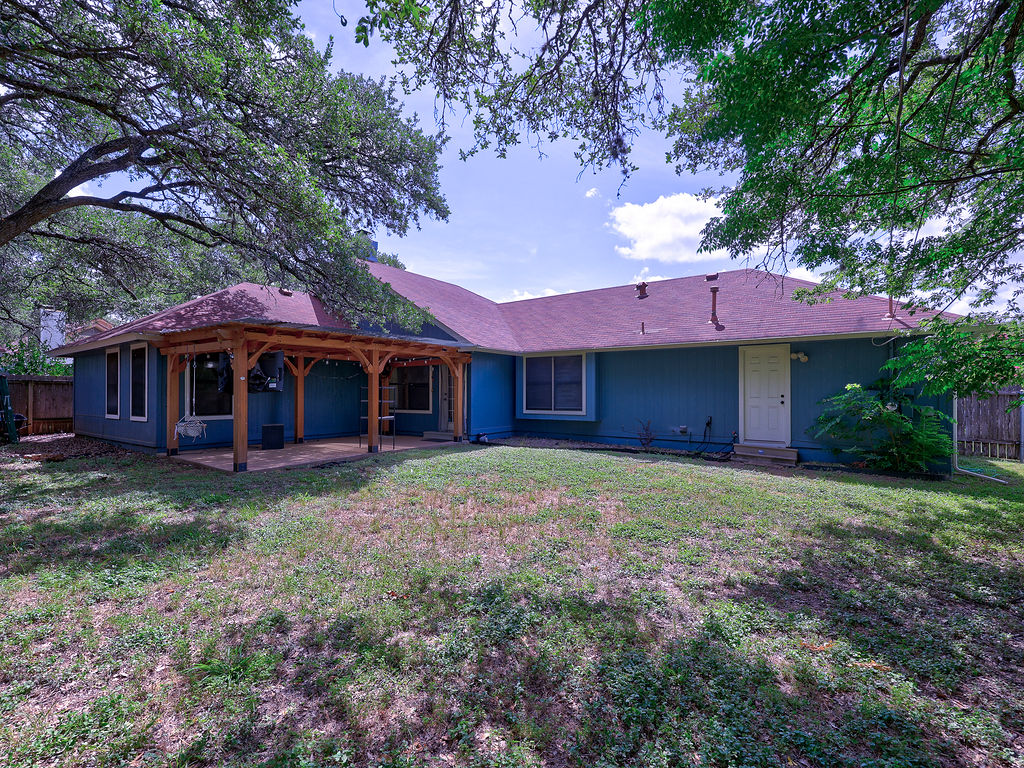5842 Secrest Drive Austin, TX 78759 - Photo 7 of 40 A spacious backyard with mature trees and a covered patio, perfect for outdoor enjoyment.