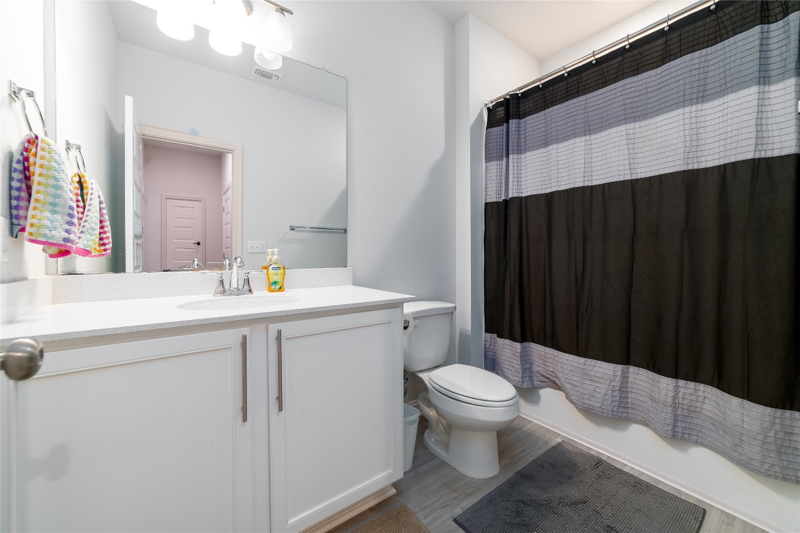 8505 Leroi Drive, Unit 358 Austin, TX 78744 - Photo 17 of 37 a bathroom with a sink a toilet a mirror and shower curtain