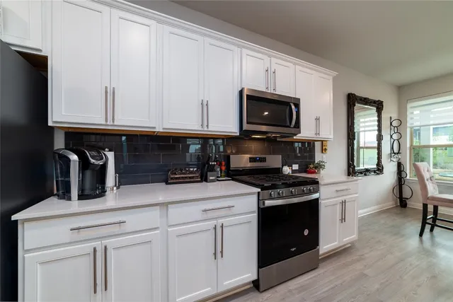 a kitchen with granite countertop white cabinets and black appliances