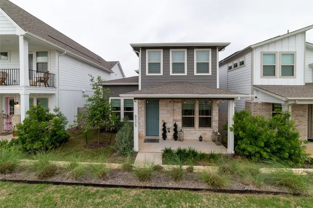 a front view of a house with a yard and potted plants