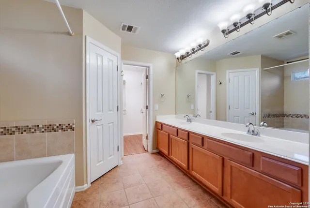 a large bathroom with a double vanity sink a large mirror and a bathtub