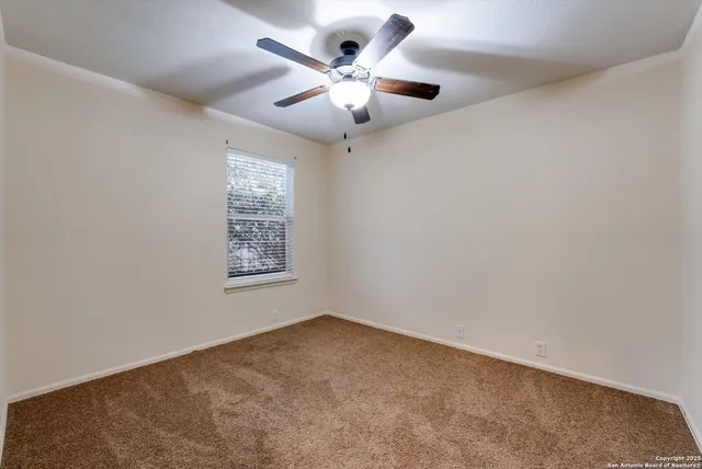 en empty room with ceiling fan and window