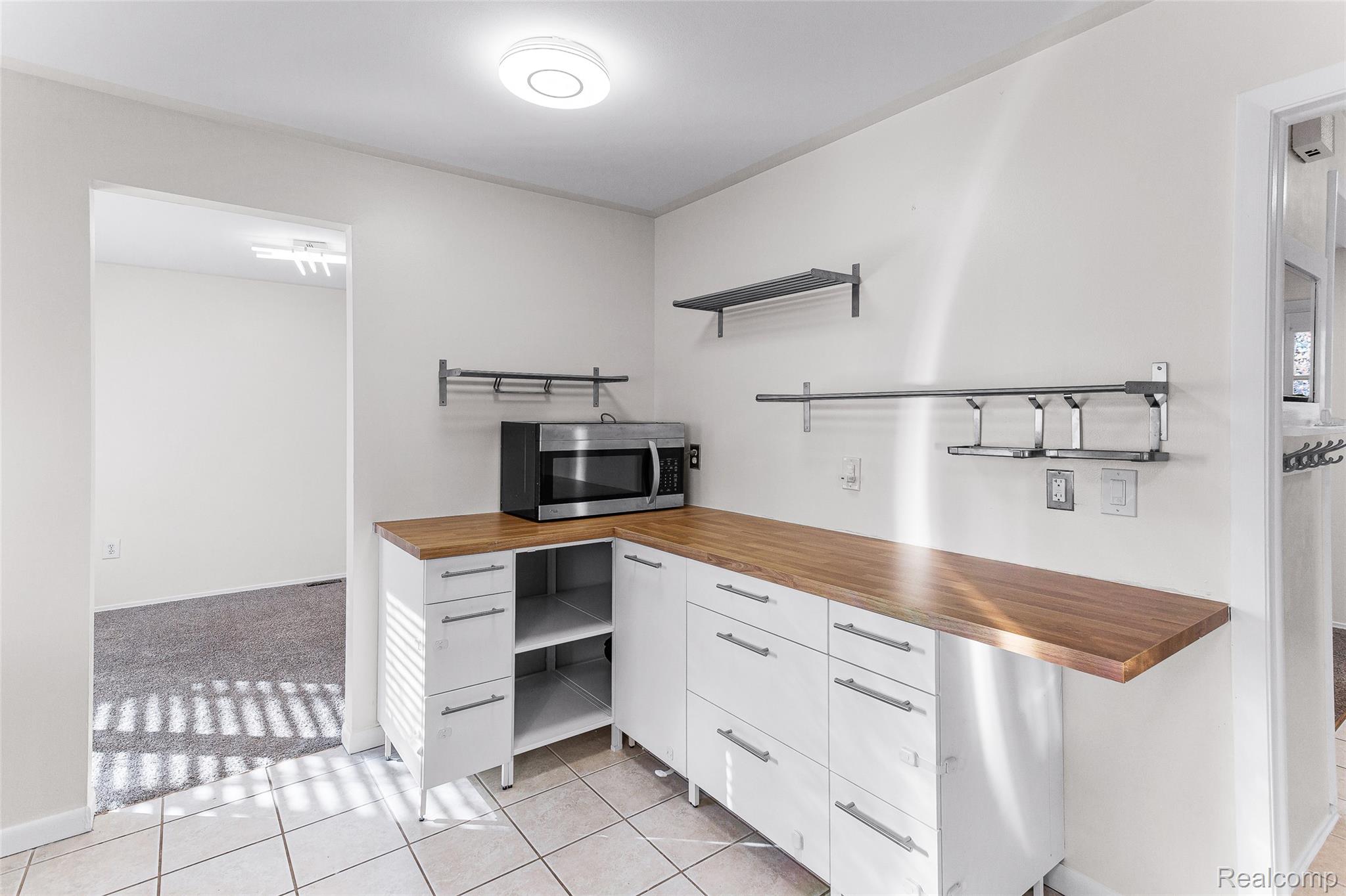 22582 Winfield Road Novi, MI 48375 - Photo 5 of 37 White cabinetry with wood-finish countertops, stainless steel microwave, and open shelving