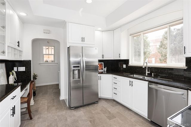 a kitchen with granite countertop a refrigerator a sink a stove and cabinets