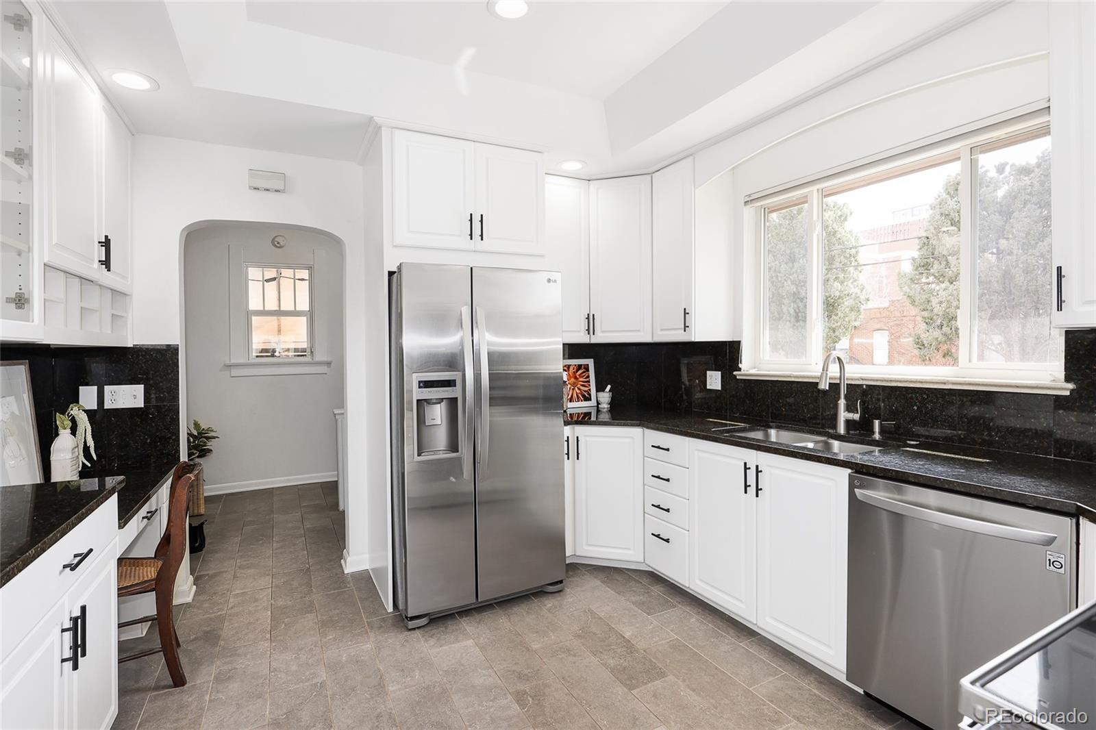 692 South Logan Street Denver, CO 80209 - Photo 11 of 40 a kitchen with granite countertop a refrigerator a sink a stove and cabinets