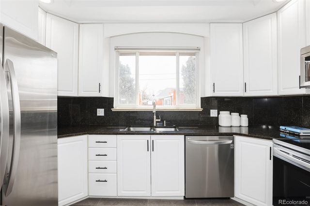 a kitchen with granite countertop a sink cabinets and stainless steel appliances