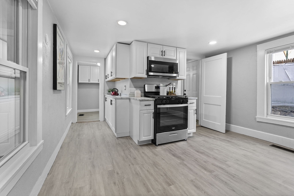 15 Reservoir Street Worcester, MA 01605 - Photo 14 of 35 a kitchen with stainless steel appliances a stove top oven a refrigerator a sink and white cabinets with wooden floor