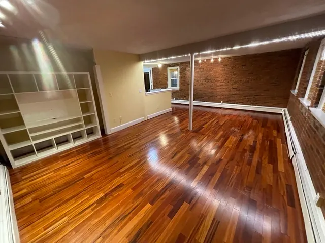 a view of an empty room with wooden floor and door