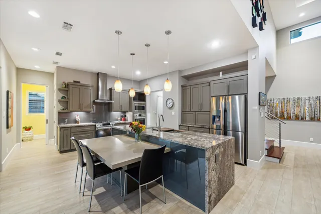 a kitchen with stainless steel appliances granite countertop a table chairs and a refrigerator