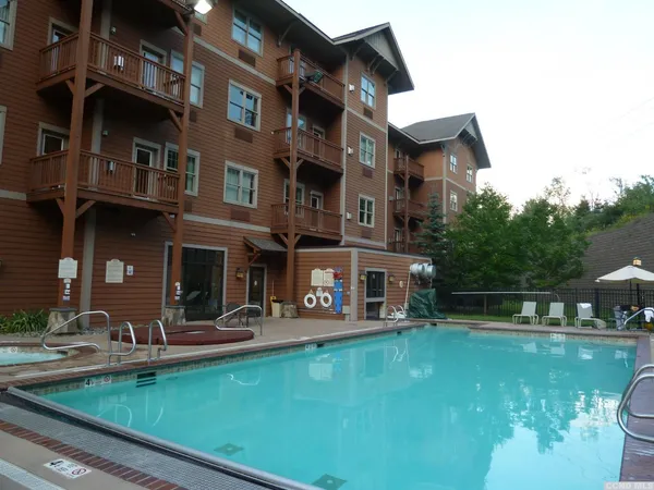 a house view with swimming pool and chairs