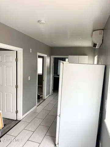 a view of a refrigerator in kitchen and an empty room