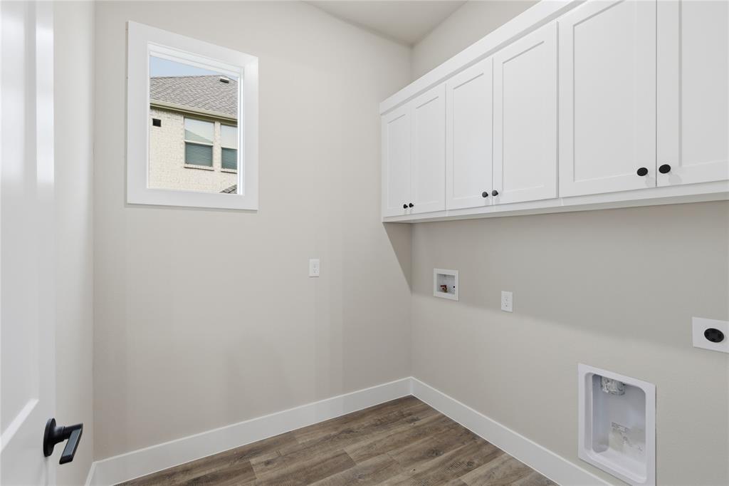 702 Anne Road Van Alstyne, TX 75495 - Photo 10 of 27 Utility room featuring white shaker-style cabinetry with black hardware, wood-finish flooring, and a single window with white trim