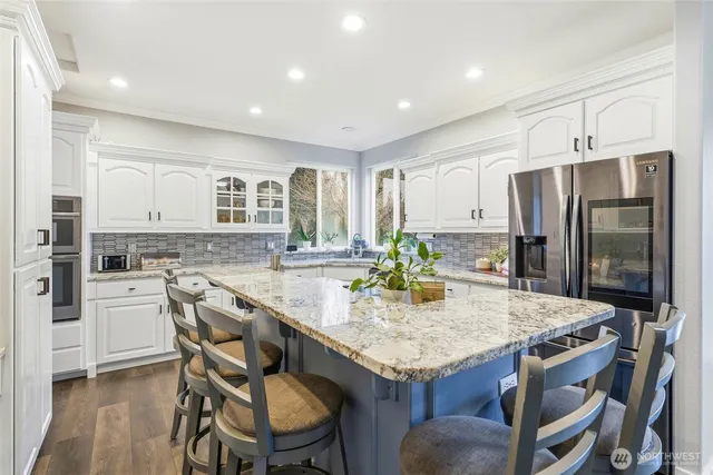 a kitchen with stainless steel appliances a dining table chairs stove and refrigerator