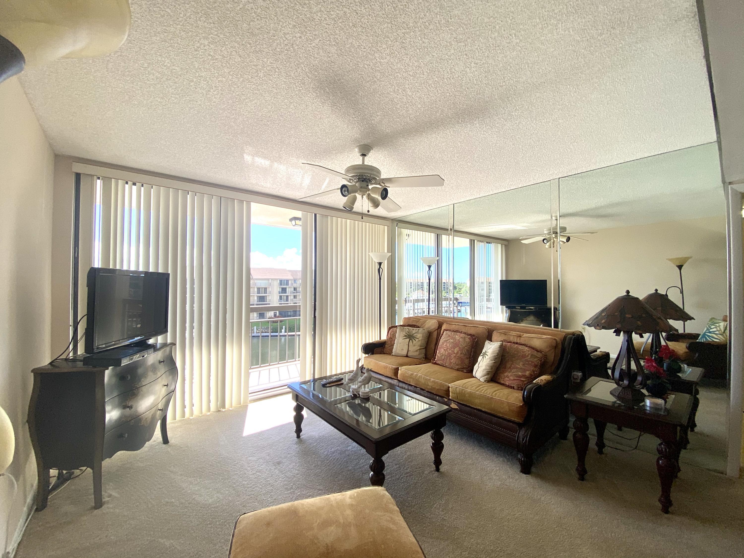 2301 Marina Isle Way, Unit 503 Jupiter, FL 33477 - Photo 38 of 45 a living room with furniture a flat screen tv and a large window