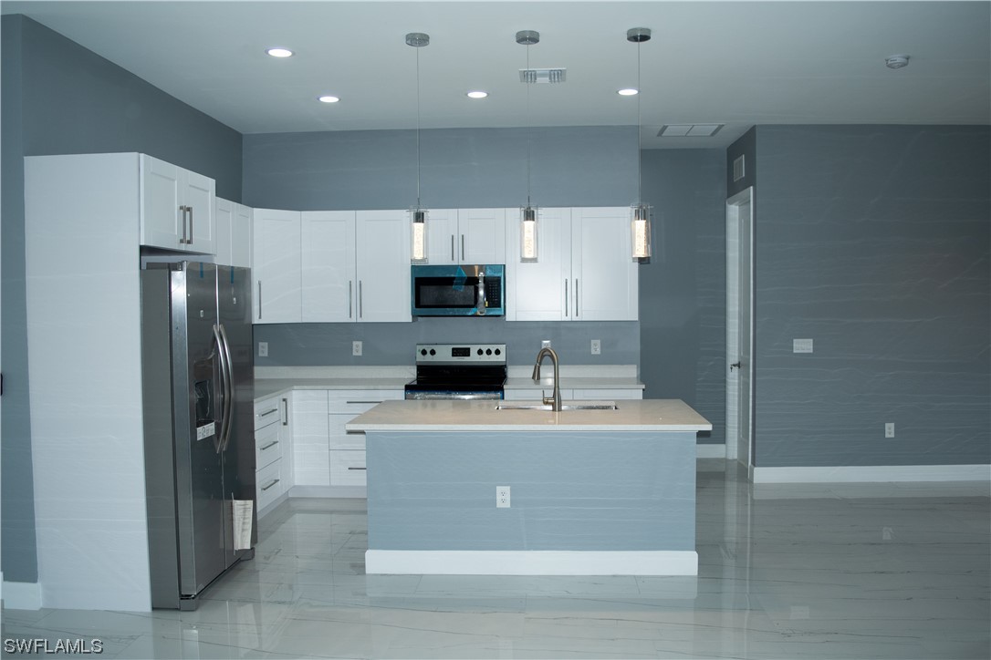 3718 41st Street Southwest Lehigh Acres, FL 33976 - Photo 10 of 28 a kitchen with kitchen island stainless steel appliances a sink a stove a microwave and cabinets