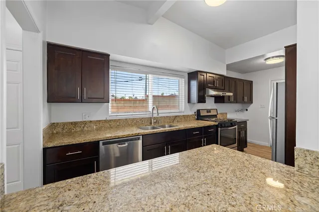 a kitchen with stainless steel appliances granite countertop a sink a stove and a wooden floors