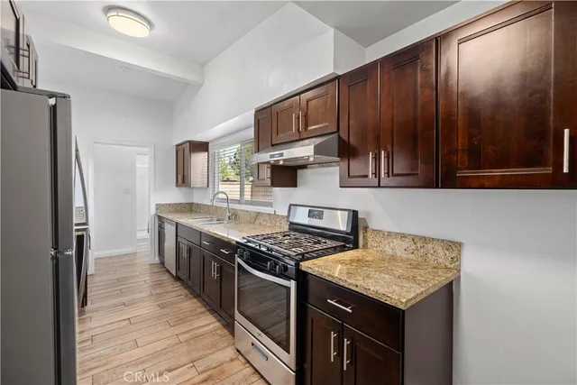 a kitchen with stainless steel appliances granite countertop a refrigerator a stove and a sink