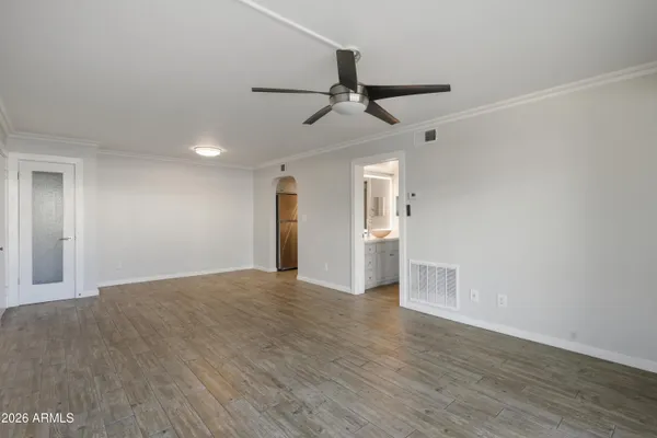 a view of empty room with wooden floor and ceiling fan