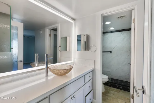 a en suite bathroom with a granite countertop sink and a mirror