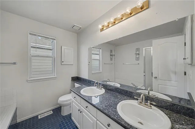 a bathroom with a granite countertop double vanity sink and a mirror