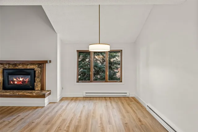 a view of an empty room with a fireplace and wooden floor