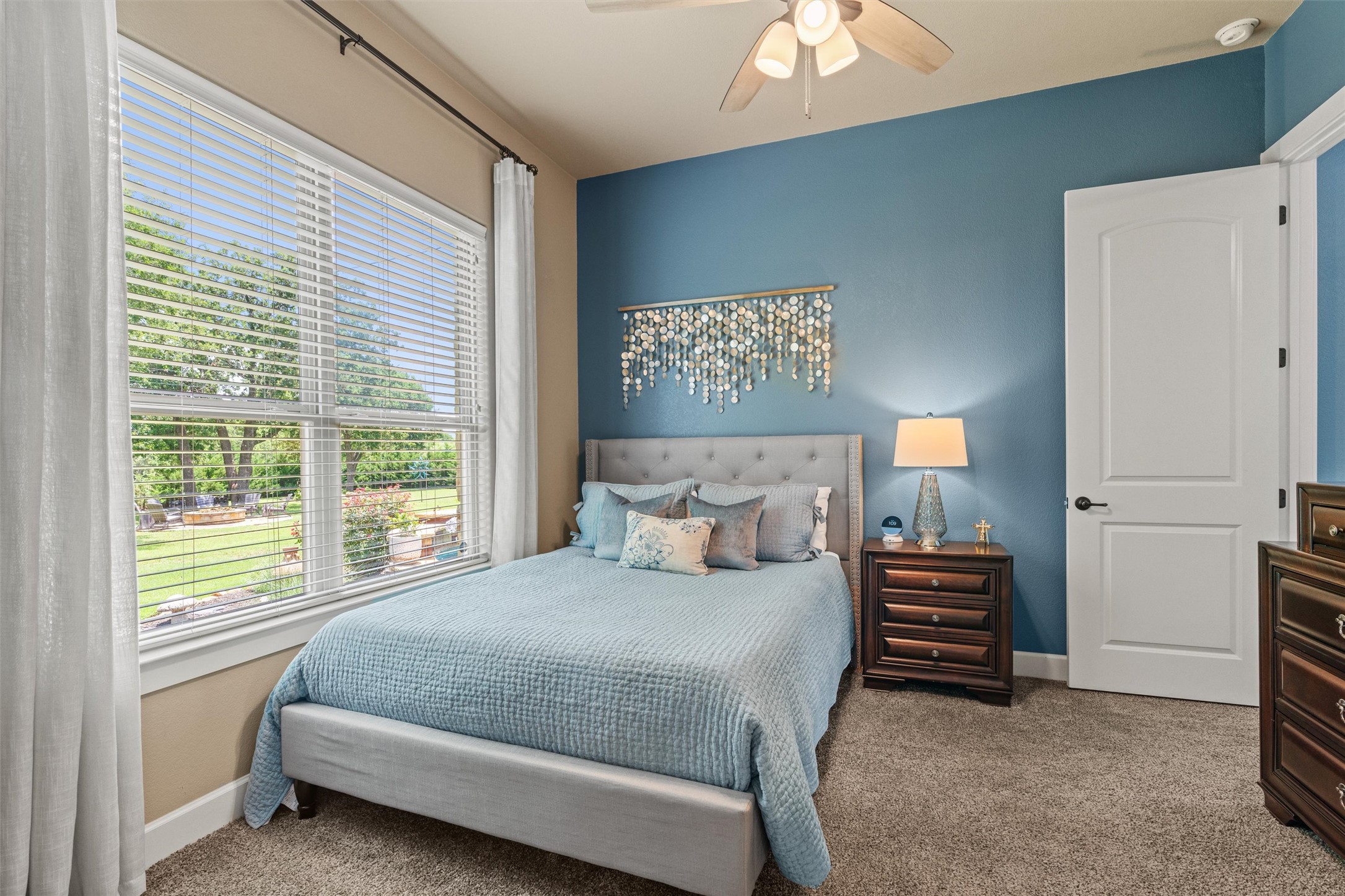 104 Adobe Cove Georgetown, TX 78633 - Photo 25 of 40 A well-lit bedroom with a wide window overlooking a lush green yard, featuring a ceiling fan for comfort.