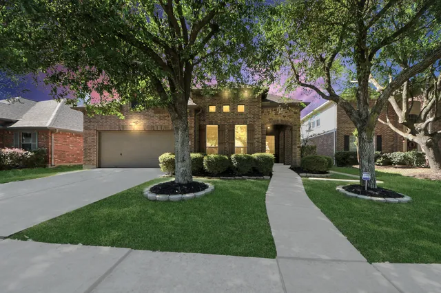 a front view of a house with garden and trees