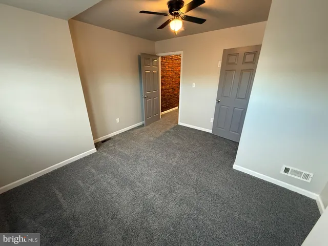 an empty room with closet and a chandelier fan