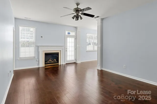 a view of a livingroom with a fireplace a ceiling fan and windows