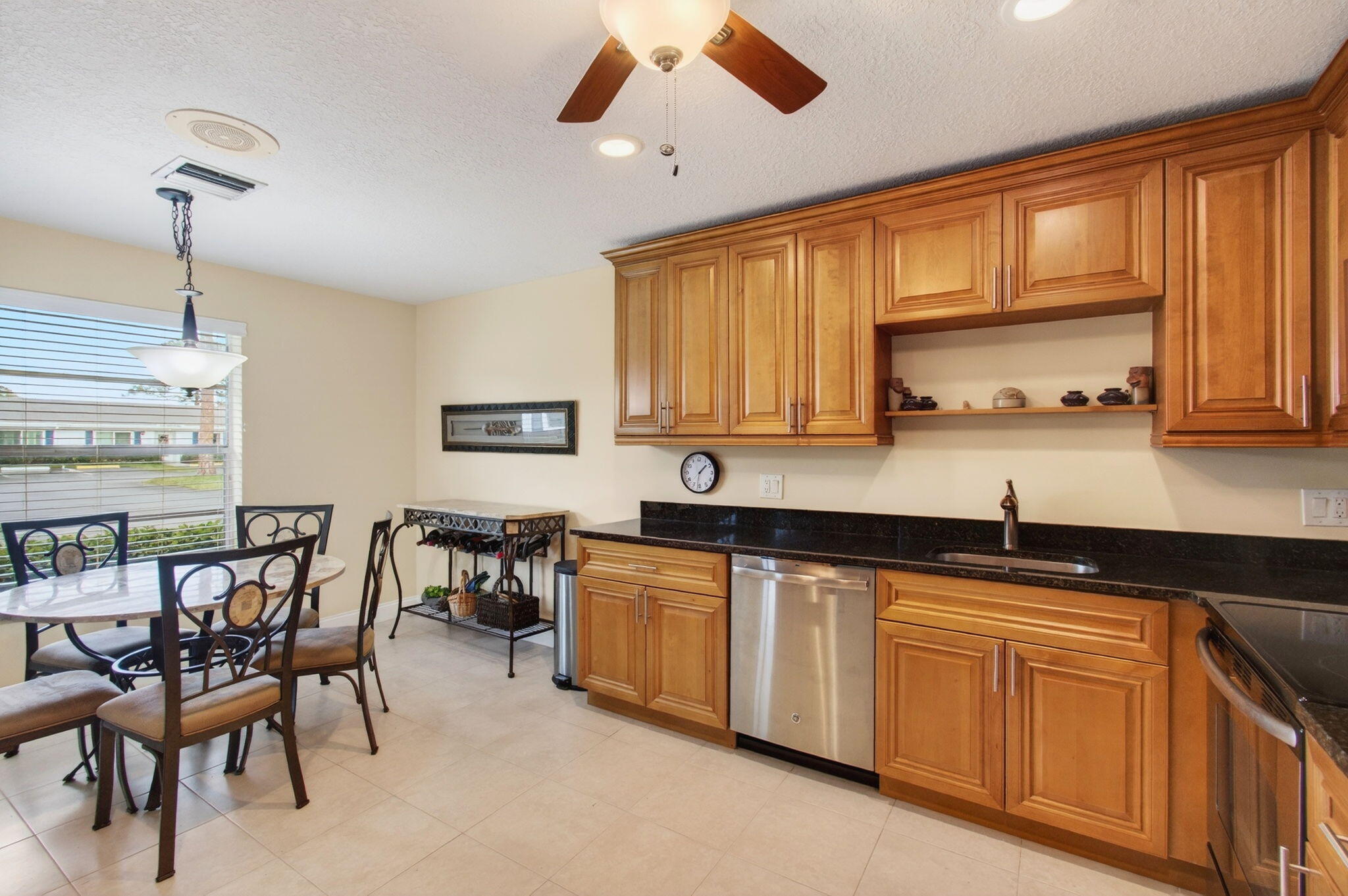 5263 Privet Place, Unit D Delray Beach, FL 33484 - Photo 6 of 60 a kitchen with stainless steel appliances granite countertop wooden cabinets a dining table and chairs