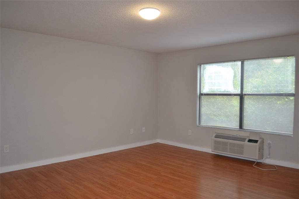 701 West Sycamore Street, Unit 207 Denton, TX 76201 - Photo 1 of 10 Unfurnished room with wood-type flooring and a wall unit AC